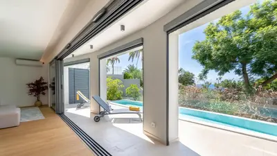 an open living room with sliding glass doors and a pool at Acqua Sensation Suites by LovelyStay in Funchal