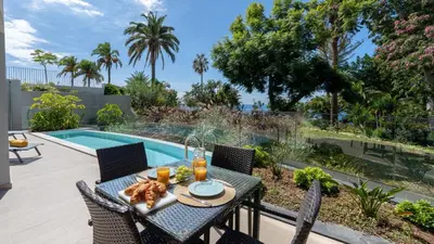 a patio with a table and chairs next to a swimming pool at Acqua Sensation Suites by LovelyStay in Funchal