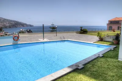 a swimming pool with the ocean in the background at Monumental Apartment in Funchal