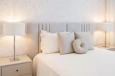 a bedroom with a bed with white pillows and two lamps at Casa Graminho in Ponta do Sol