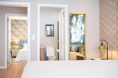 a white bedroom with a bed and a bathroom at Casa Graminho in Ponta do Sol