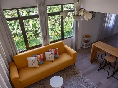 a living room with a yellow couch with pillows at Traditional Madeira House Garden, Terrace & BBQ in Ribeira Brava