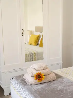 a mirror with towels and a sunflower on a bed at Traditional Madeira House Garden, Terrace & BBQ in Ribeira Brava