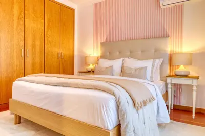 a bedroom with a large white bed with wooden cabinets at Alzira's Place, a Home in Madeira in Ponta do Sol