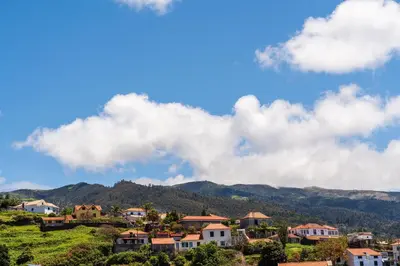 a village on a hill with mountains in the background at Casa do Paulinhos - Vista Panorâmica, Natureza, Wi-Fi Rápido in Estreito da Calheta