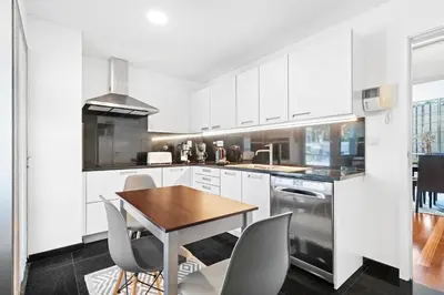a kitchen with white cabinets and a wooden table and chairs at Vista Savoy Apartamento in Funchal