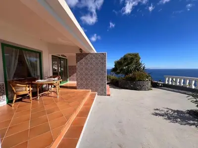 a patio with a table and chairs on a house at Private Oceanfront Cottage with 180 degree Sea View, 100 m Terrace in Funchal