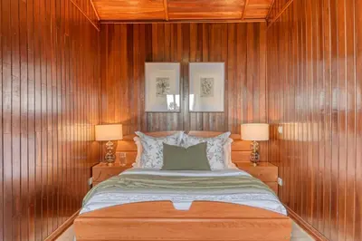 a bedroom with wooden walls and a bed with two lamps at Chalet do Relógio d'Água, a Home in Madeira in Ponta do Sol