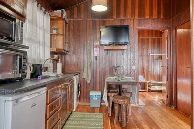 a kitchen with wooden cabinets and a tv on the wall at Chalet do Relógio d'Água, a Home in Madeira in Ponta do Sol