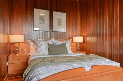 a bedroom with a bed with wood paneling and two lamps at Chalet do Relógio d'Água, a Home in Madeira in Ponta do Sol