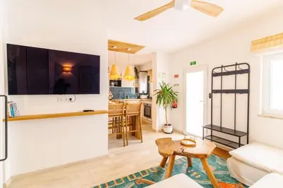a living room with a couch and a tv on a wall at Casa Phoebe - NEW Renovated Burgau Apartment Sleeps 5 - Beach 1 min in Burgau