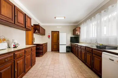 a large kitchen with wooden cabinets and a white refrigerator at Villa do Carmo by GALMI in Funchal