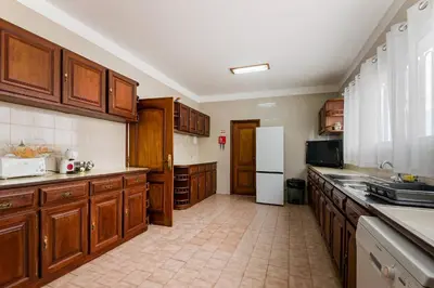 a large kitchen with wooden cabinets and a white refrigerator at Villa do Carmo by GALMI in Funchal
