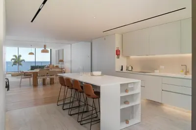 a kitchen with white cabinets and a table with chairs at Savoy Monumentalis VII by An Island Apart in Funchal