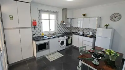 a kitchen with white cabinets and a table with a tableablish at Lower Floor In Flor do Campo - Santana in Santana