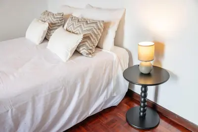 a white bed with pillows and a lamp on a table at João Loft II by Mth in Campanário