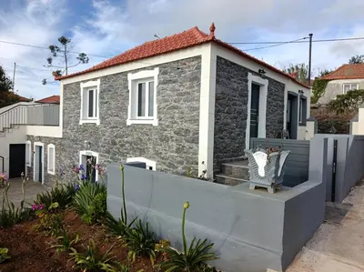 a front door of a house with a stone wall at Adelaide's Cottage in Ponta do Pargo