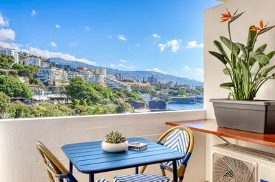 a blue table and chairs on a balcony with a view at Aida's Place, a Home in Madeira in Funchal