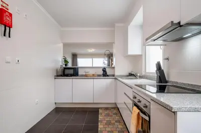 a white kitchen with white cabinets and a sink at Sunflower Stay by Homie in Caniço