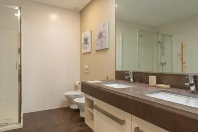 a bathroom with two sinks and a toilet and a mirror at FLH Oceanfront Luxury at Madeira Palace Residence in Funchal