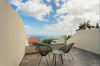two chairs and a table on a balcony with the ocean at Figueira House in Santa Cruz