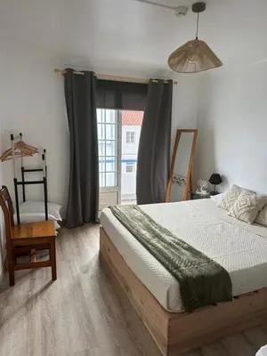 a bedroom with a bed and a chair and a window at Casinha Santa Maria in Vila do Porto