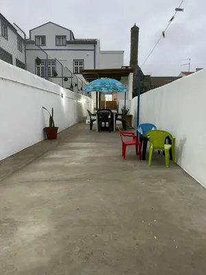a patio with chairs and a table with an umbrella at Casinha Santa Maria in Vila do Porto