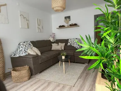 a living room with a brown couch and some plants at Casinha Santa Maria in Vila do Porto