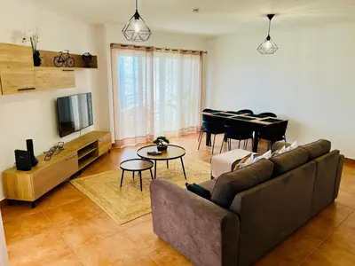 a living room with a couch and a dining room at Maria do Mar Apartment in Caniço