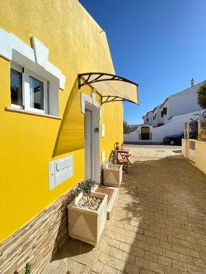 a yellow building with a table and an umbrella at Casa do Sol in Sagres