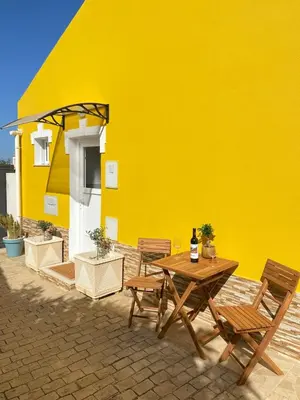 a yellow wall with a wooden table and chairs at Casa do Sol in Sagres