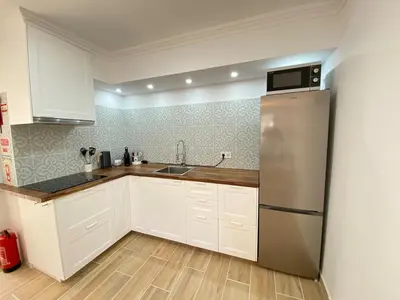 a kitchen with white cabinets and a stainless steel refrigerator at Casa do Sol in Sagres