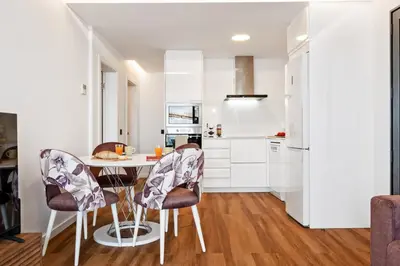 a white kitchen with a table and chairs at Luxury Seafront Escape I in Caniçal