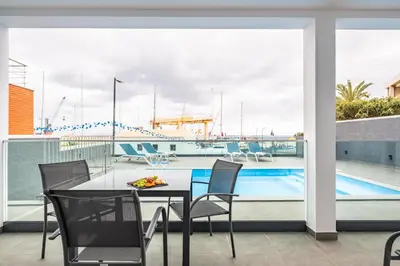 a balcony with a table and chairs and a swimming pool at Luxury Seafront Escape I in Caniçal