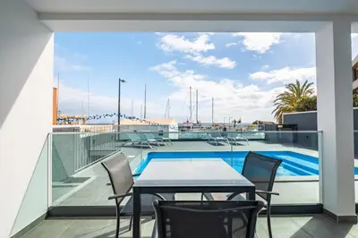 a balcony with a table and chairs and a swimming pool at Luxury Seafront Escape II in Caniçal