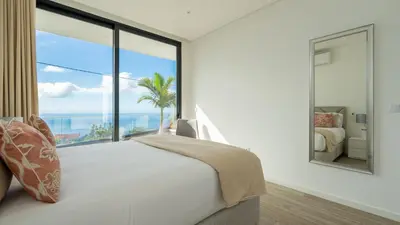 a bedroom with a large window with a view of the ocean at Moonlight Villa by LovelyStay in Estreito da Calheta