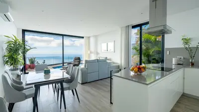 a kitchen and living room with a view of the ocean at Moonlight Villa by LovelyStay in Estreito da Calheta
