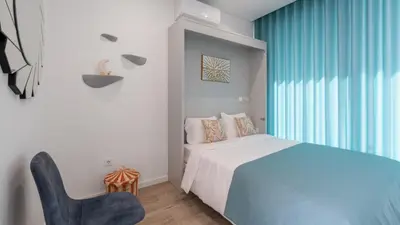 a bedroom with a bed and a blue chair at Moonlight Villa by LovelyStay in Estreito da Calheta