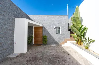 a brick house with a wooden door and some plants at Moonlight Villa by LovelyStay in Estreito da Calheta