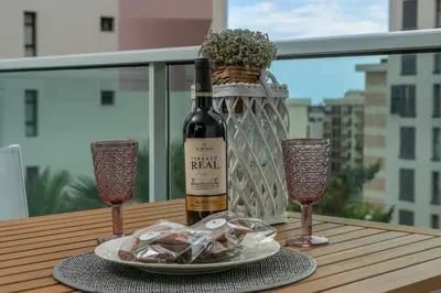 a bottle of wine and two glasses on a table at Alameda Formosa Varanda Zona Turística Funchal in Funchal
