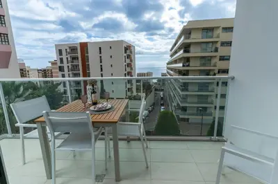 a balcony with a table and chairs and a view of a city at Alameda Formosa Varanda Zona Turística Funchal in Funchal