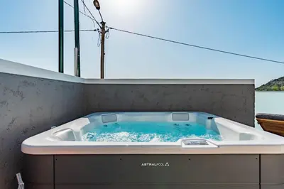a wooden table with glasses of wine and an umbrella at Villa Bisa II, jacuzzi and sea view in Arco da Calheta