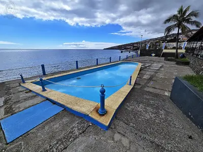 a large blue swimming pool next to the water at Dª Xica Holidays in Santa Cruz