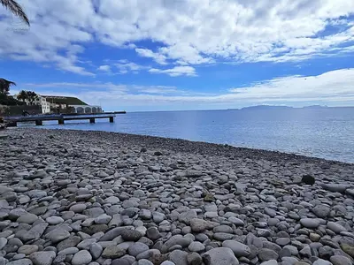 a rocky beach with a pier in the water at Dª Xica Holidays in Santa Cruz