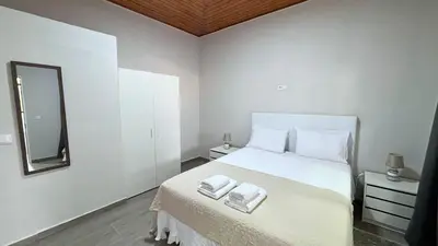 a white bedroom with a bed with two towels on it at Ninho's Sea View By Sam Houses in Ribeira Brava
