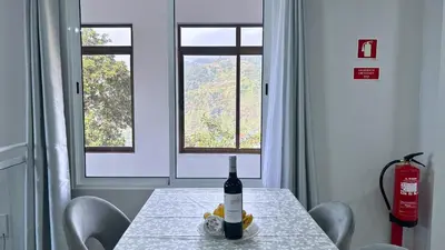 a bottle of wine on a table in a room with windows at Ninho's Sea View By Sam Houses in Ribeira Brava