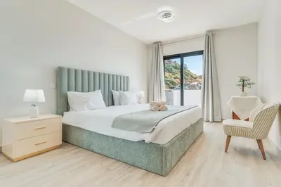 a bedroom with a large bed and a chair at Vista Magnífica I by Holiday Rental Madeira in Campanário