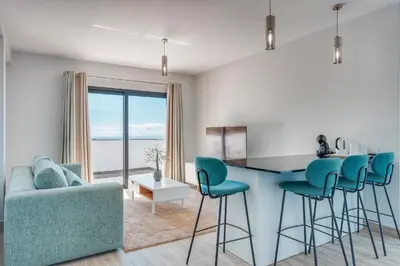 a living room with a blue couch and a table with chairs at Vista Magnífica I by Holiday Rental Madeira in Campanário