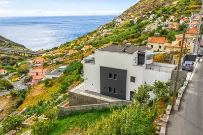 a white house on a hill next to the ocean at Vista Magnífica I by Holiday Rental Madeira in Campanário
