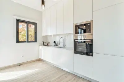 a white kitchen with white cabinets and a window at Sonhos na Iha III by Holiday Rental Madeira in Campanário